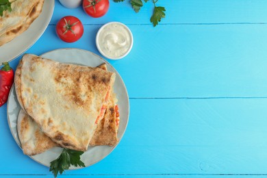 Photo of Halves of tasty calzone, tomato and sauce on light blue table, flat lay. Space for text