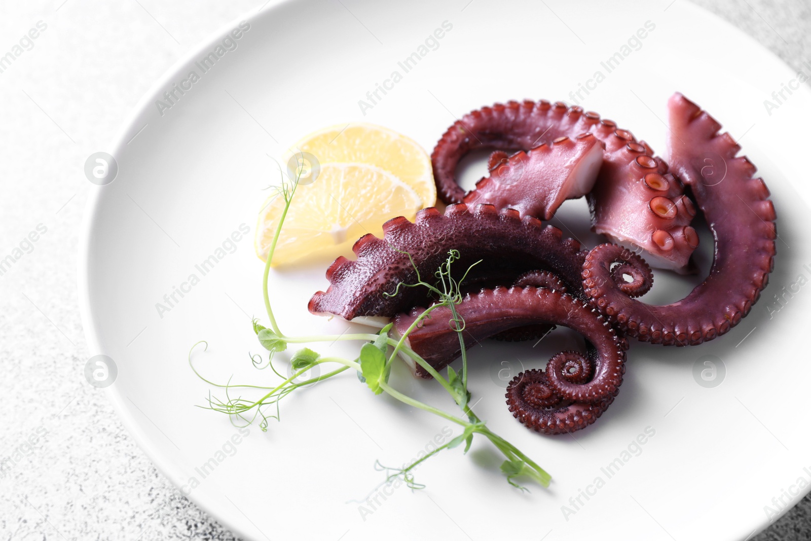 Photo of Appetizing octopus tentacles on grey table, closeup