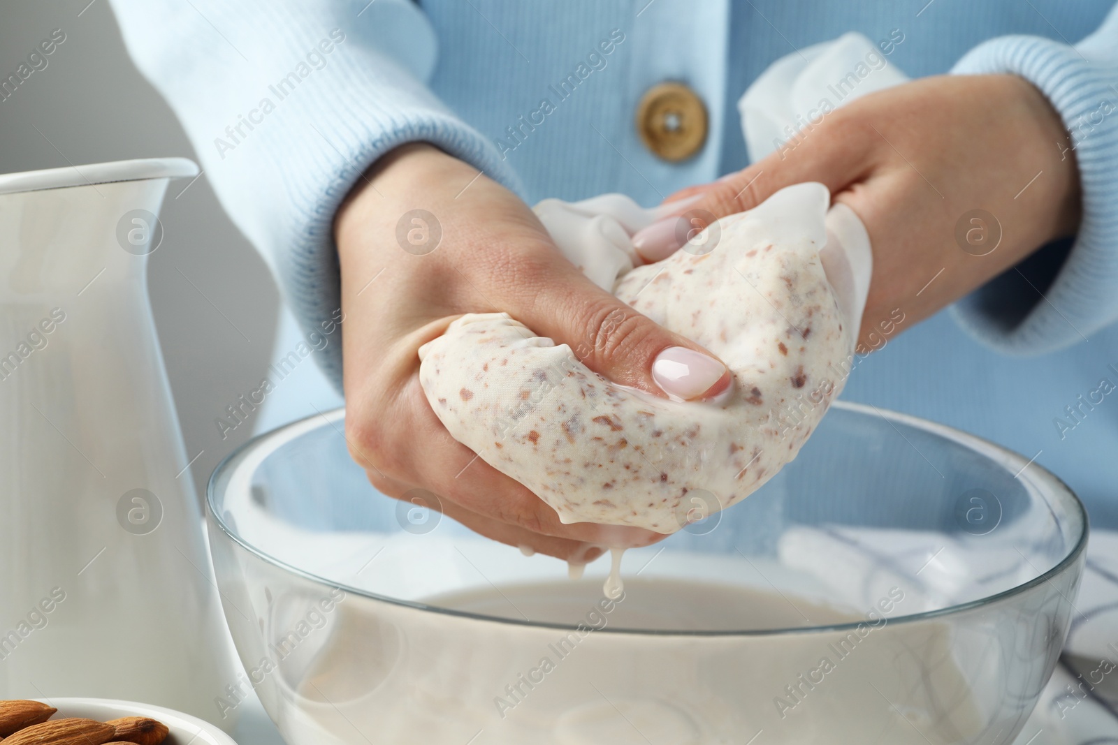 Photo of Woman making almond milk at table, closeup