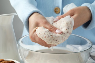 Woman making almond milk at table, closeup