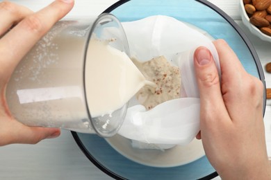 Photo of Woman making almond milk at table, top view