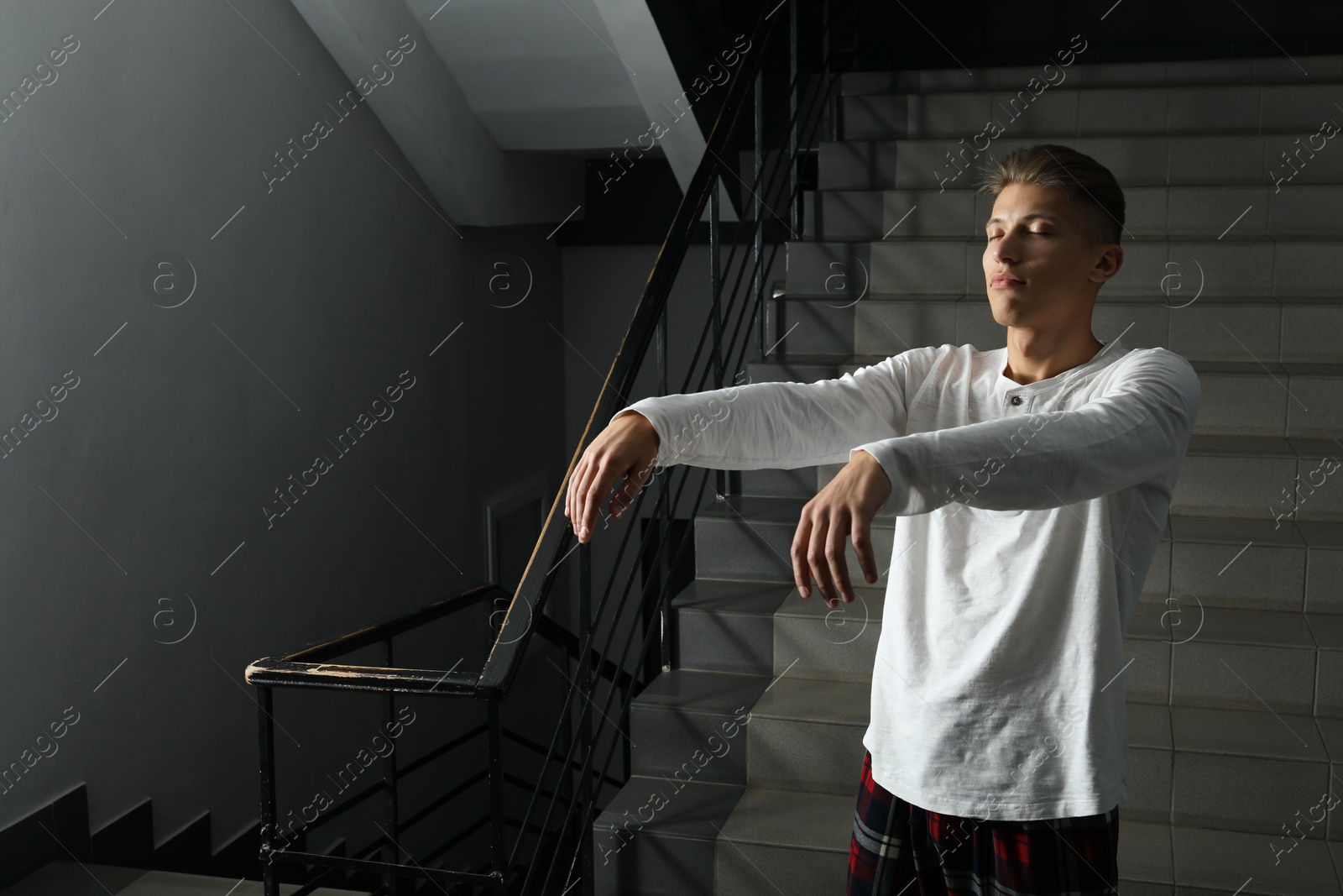 Photo of Young man suffering from sleepwalking on stairs indoors, space for text