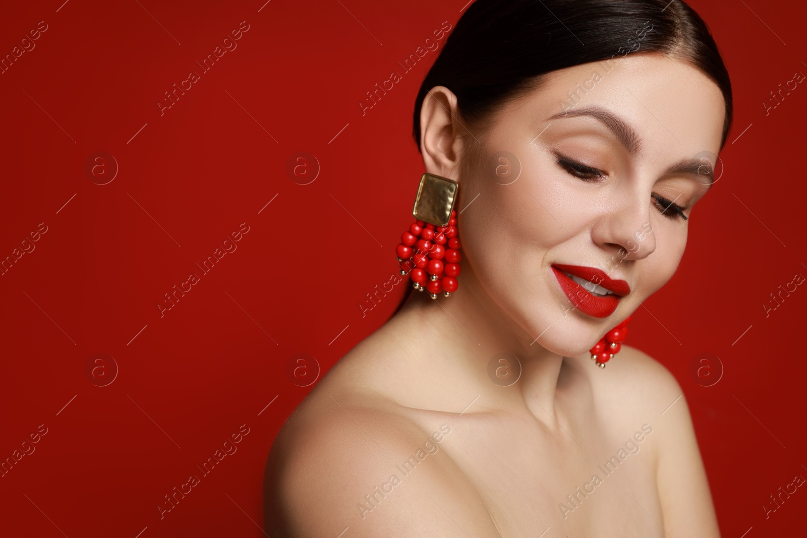 Photo of Beautiful young woman wearing elegant earrings on red background. Space for text