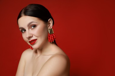 Photo of Beautiful young woman wearing elegant earrings on red background. Space for text