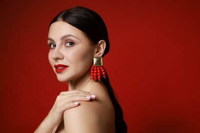 Photo of Beautiful young woman wearing elegant earrings on red background. Space for text