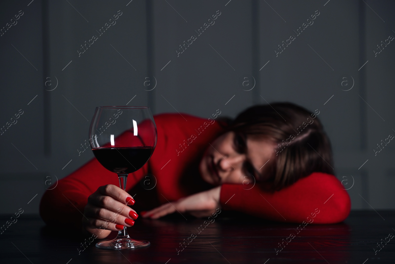 Photo of Alcohol addiction. Woman with glass of red wine at wooden table indoors, selective focus