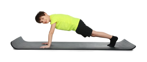 Photo of Boy exercising on fitness mat against white background. Sport activity