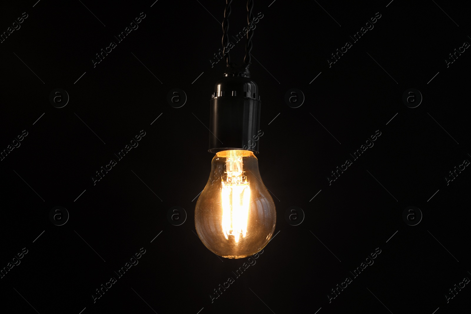 Photo of Glowing light bulb hanging on dark background