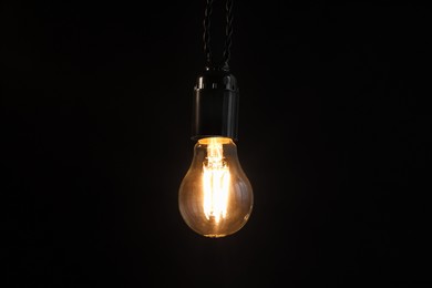 Photo of Glowing light bulb hanging on dark background