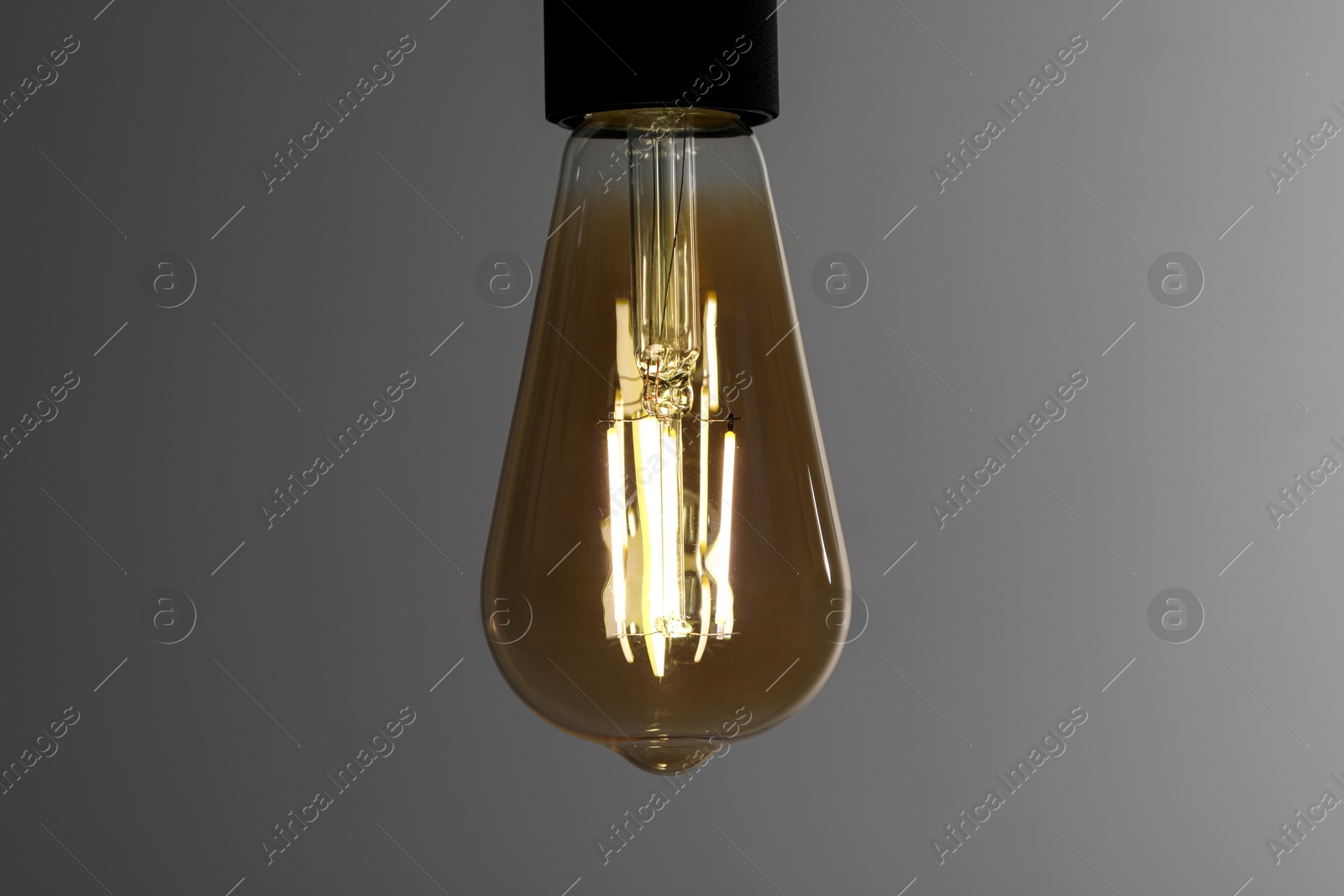 Photo of Glowing light bulb on grey background, closeup