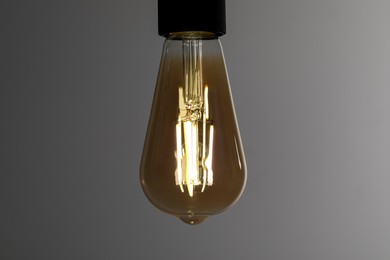 Photo of Glowing light bulb on grey background, closeup