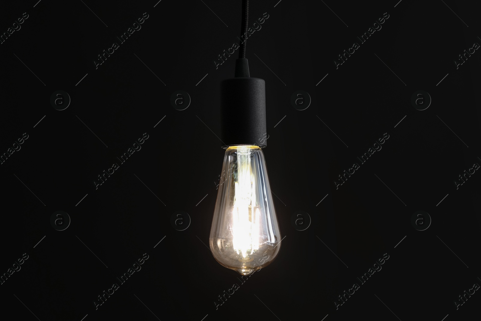 Photo of Glowing light bulb hanging on dark background