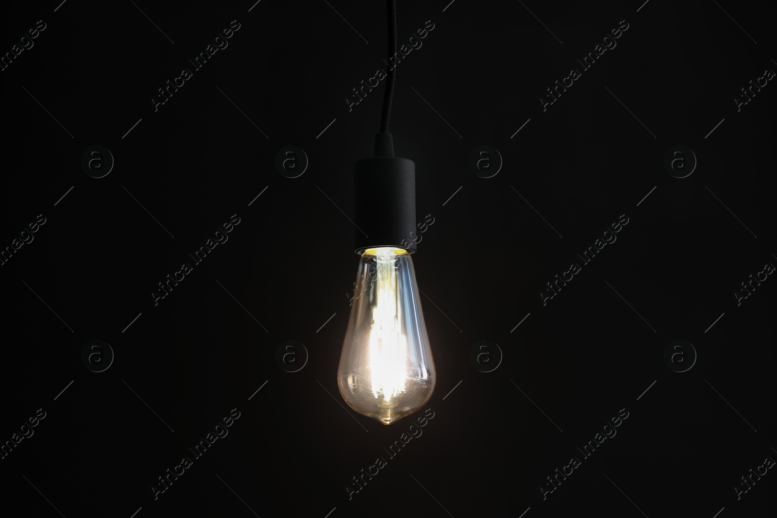 Photo of Glowing light bulb hanging on dark background