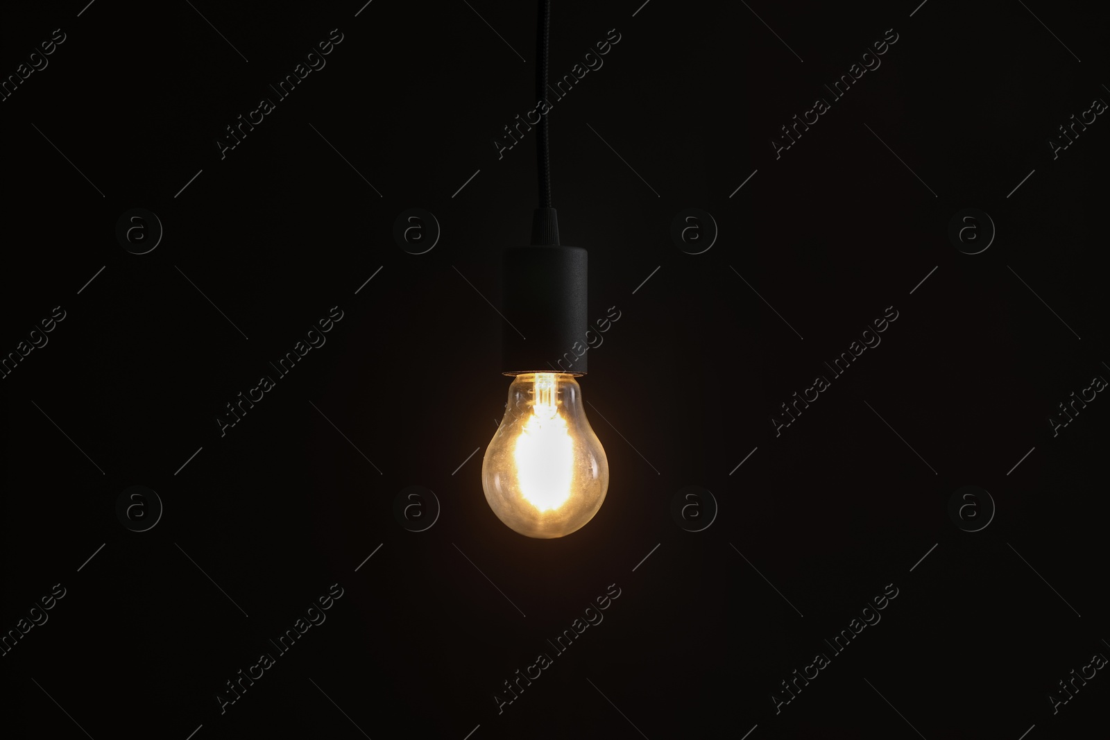 Photo of Glowing light bulb hanging on dark background