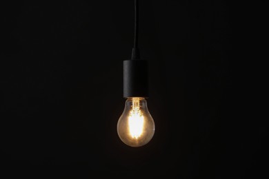 Photo of Glowing light bulb hanging on dark background