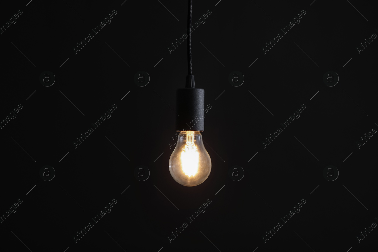 Photo of Glowing light bulb hanging on dark background