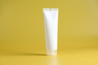 Photo of Tube of cosmetic product on yellow background