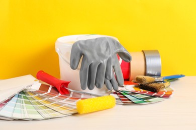 Photo of Different painter's tools on white wooden table. Decorating and design