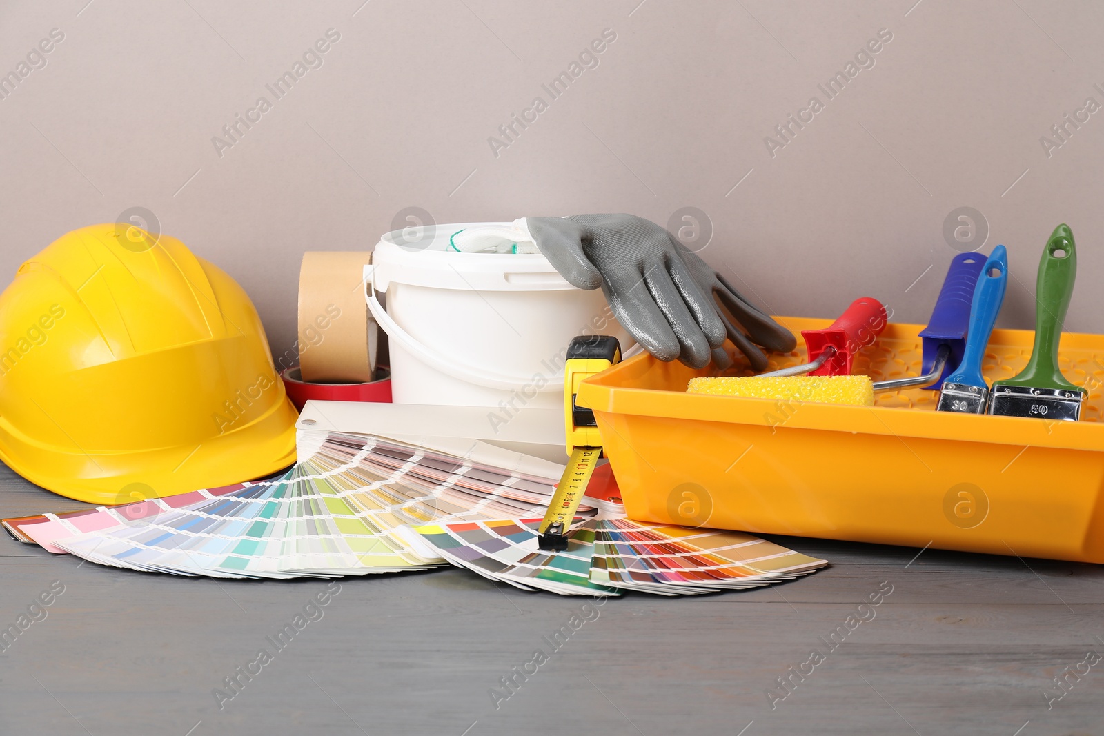 Photo of Different painter's tools on grey wooden table. Decorating and design