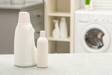 Photo of Laundry detergents on light table in bathroom. Space for text