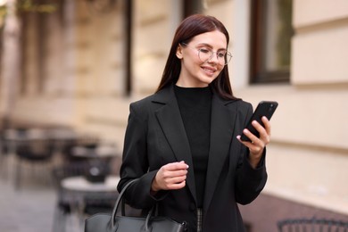 Photo of Smiling businesswoman in stylish suit with smartphone outdoors. Space for text