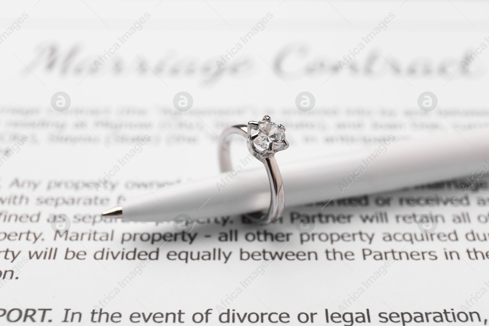 Photo of Marriage contract and pen with stylish ring, closeup