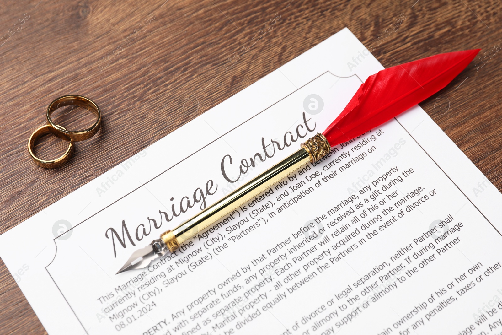 Photo of Marriage contract, pen and golden rings on wooden table, top view