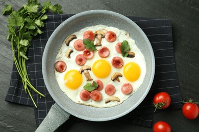 Photo of Tasty fried eggs with cut sausages and mushrooms served on black table, flat lay