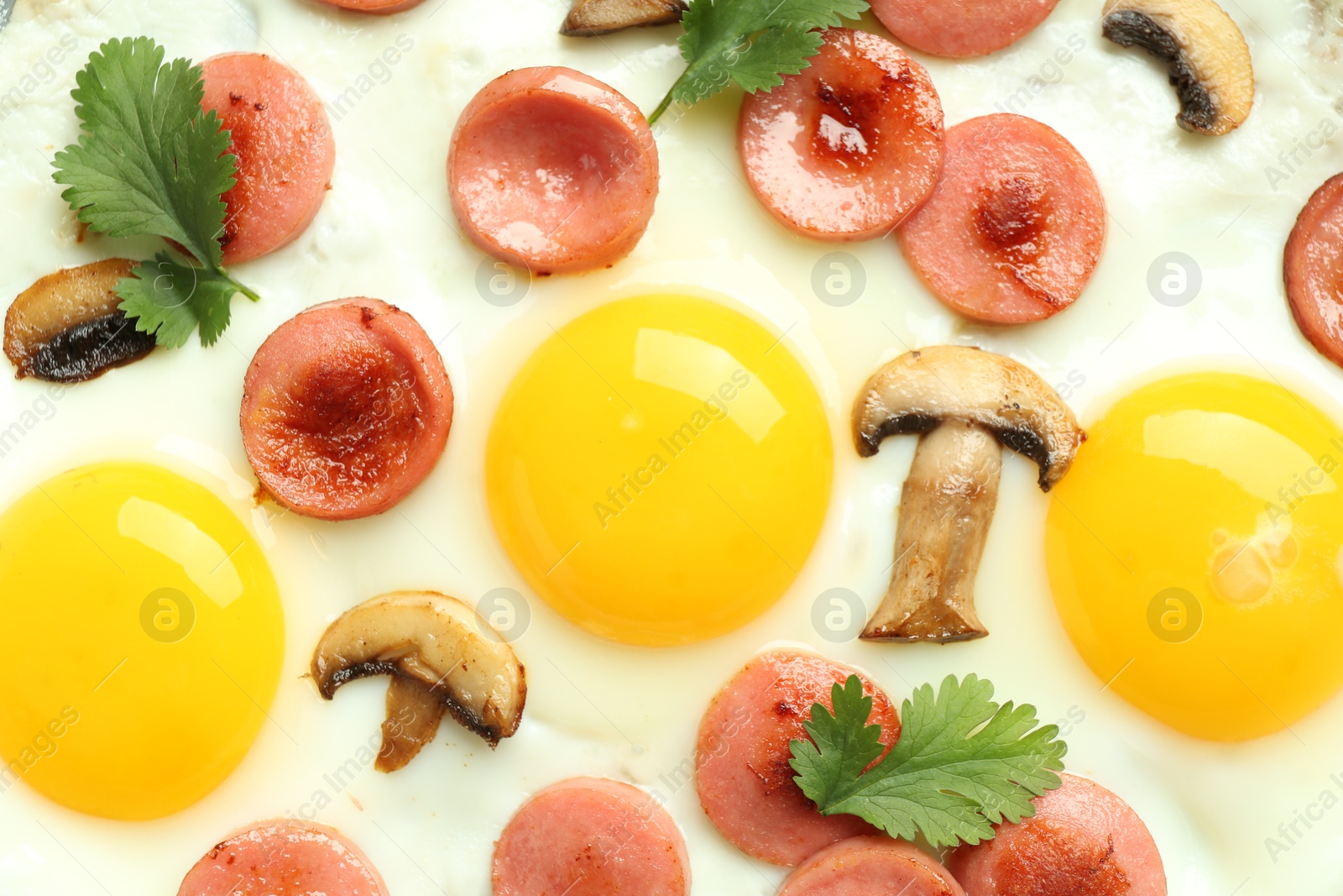 Photo of Tasty fried eggs with cut sausages, mushrooms and parsley as background, top view