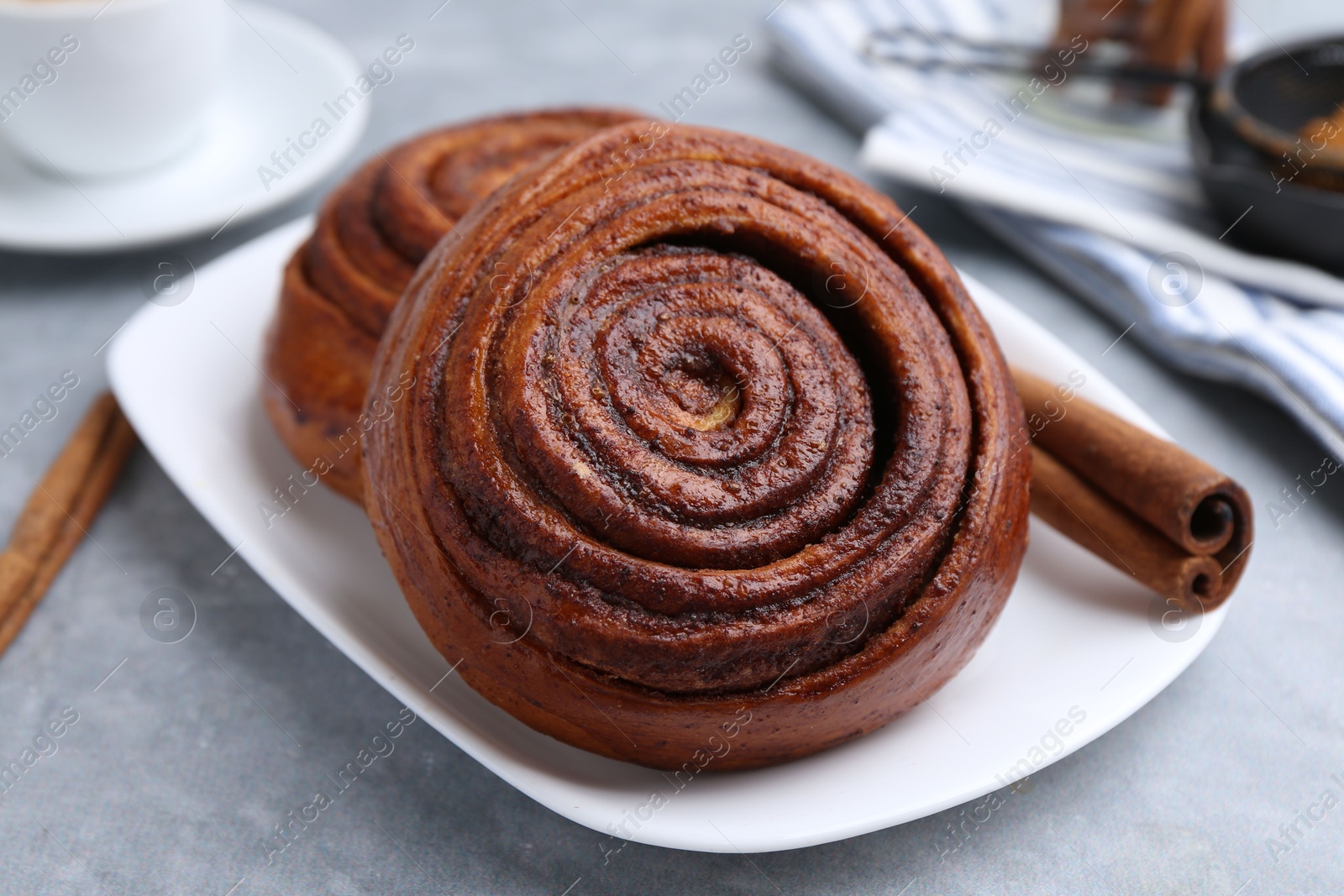 Photo of Delicious cinnamon rolls on grey table, closeup