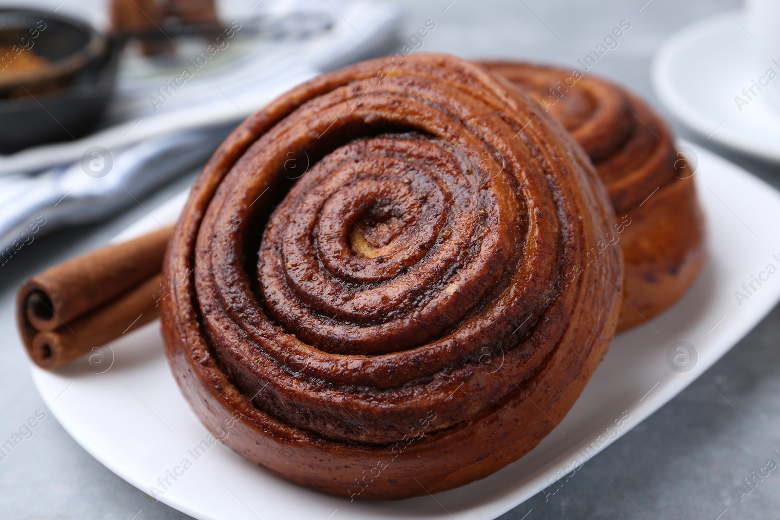 Photo of Delicious cinnamon rolls on grey table, closeup