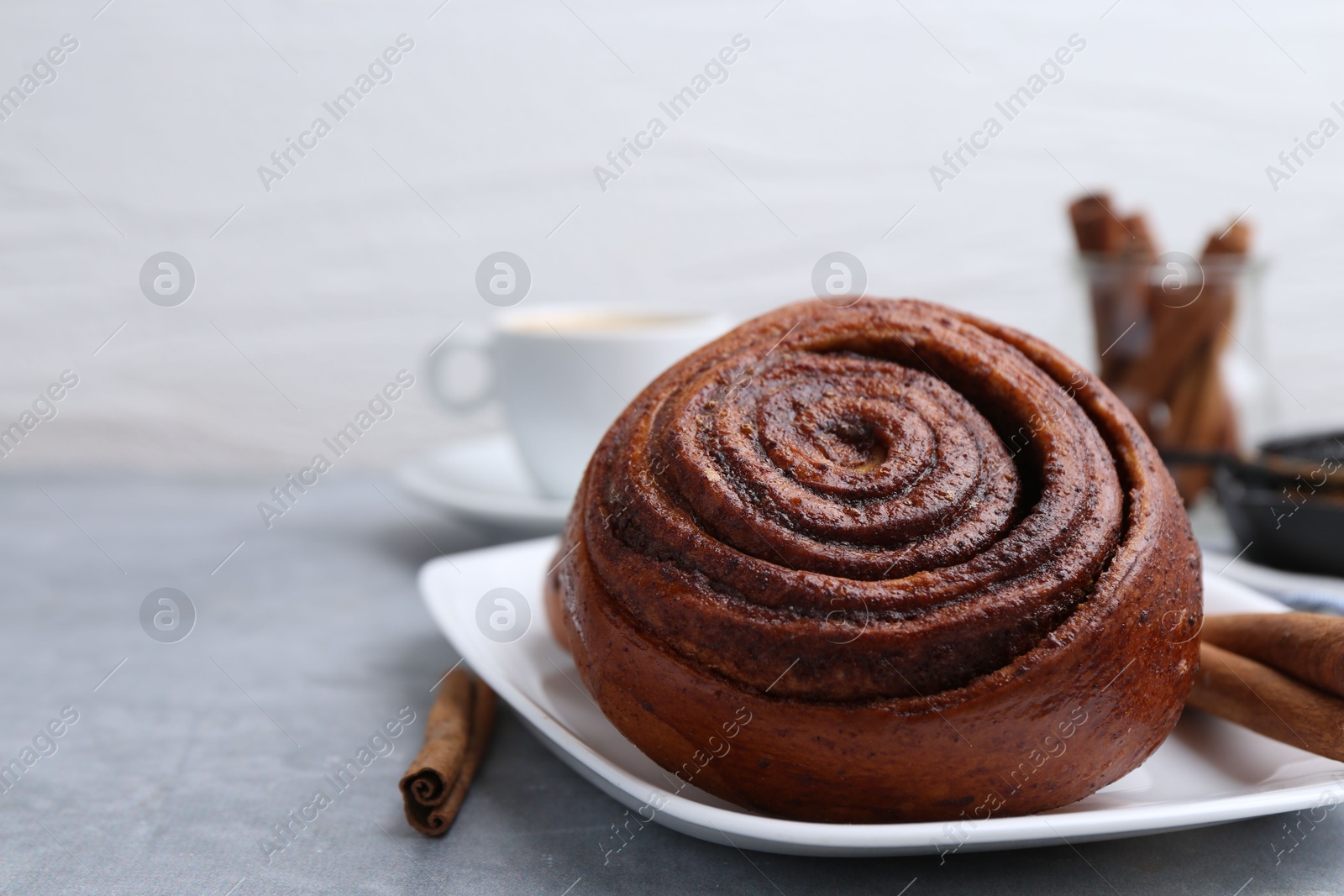 Photo of Delicious cinnamon roll on grey table, closeup. Space for text