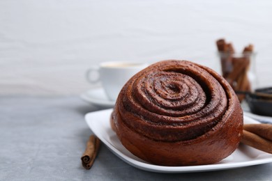 Photo of Delicious cinnamon roll on grey table, closeup. Space for text