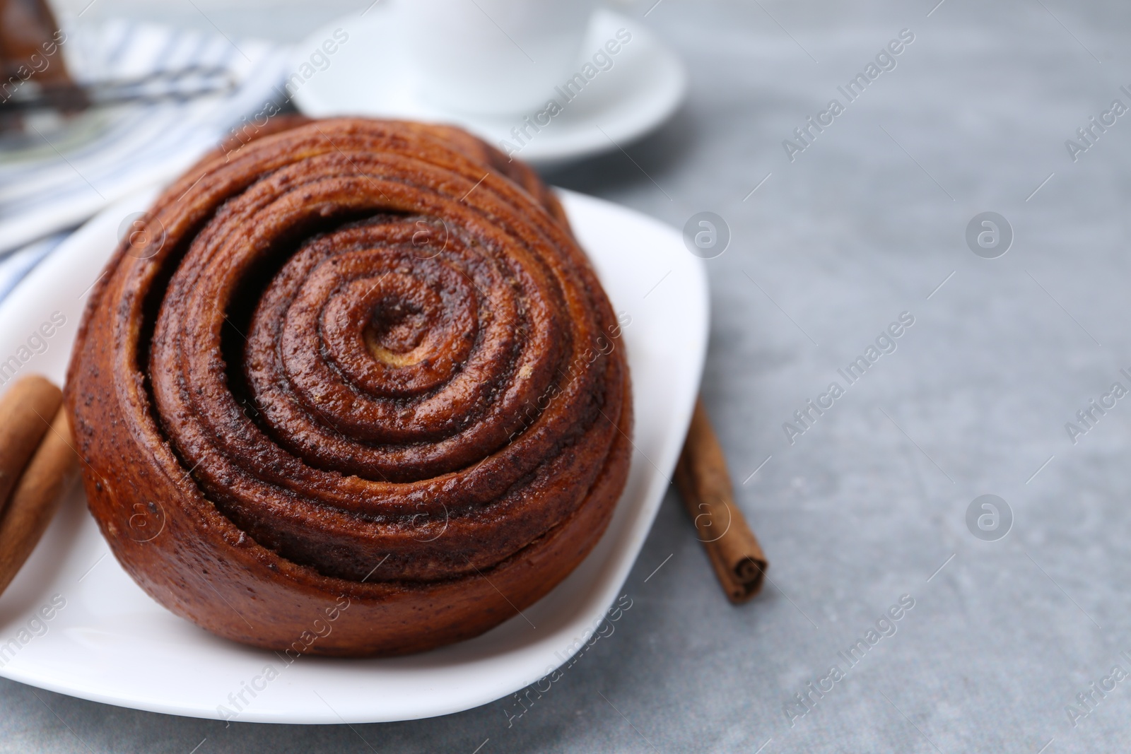 Photo of Delicious cinnamon roll on grey table, closeup. Space for text