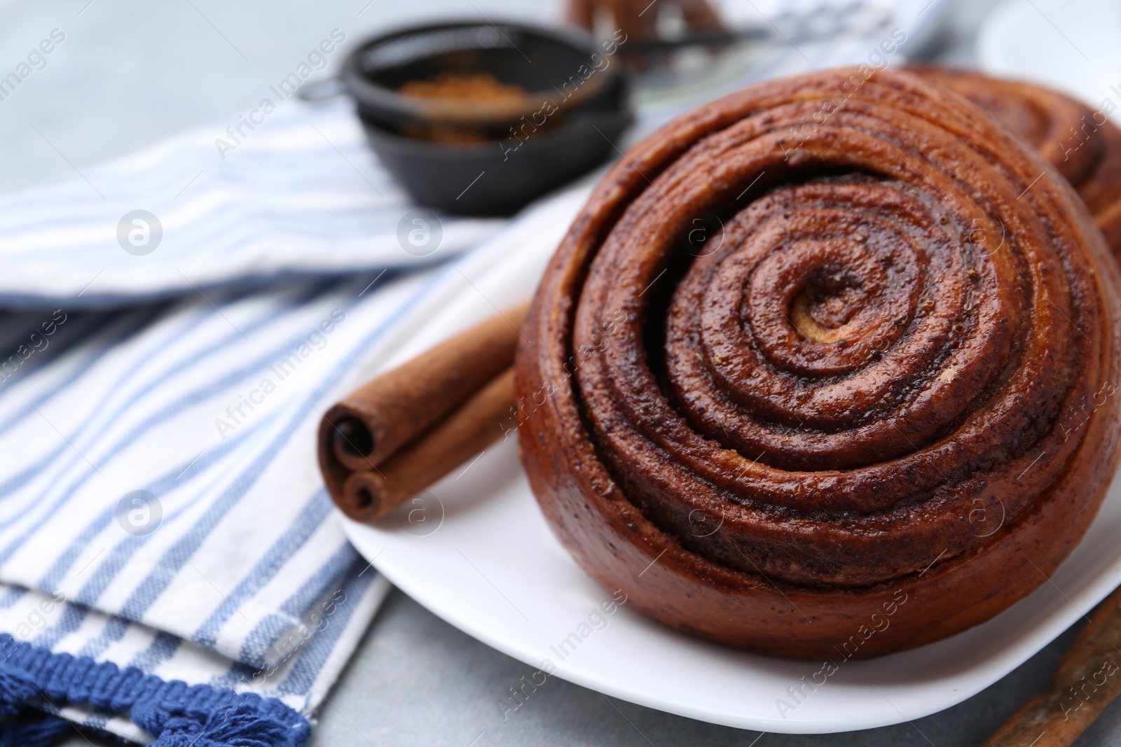 Photo of Delicious cinnamon roll on grey table, closeup