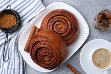 Photo of Delicious cinnamon rolls served with coffee on grey table, flat lay