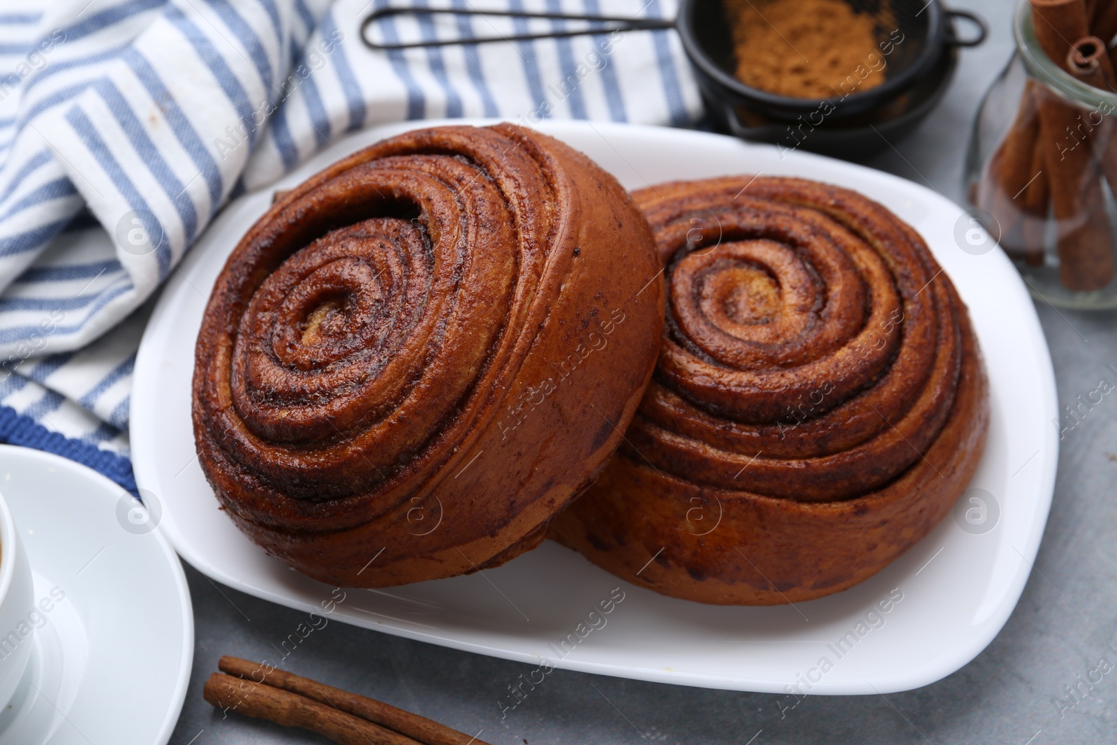 Photo of Delicious cinnamon rolls on grey table, closeup