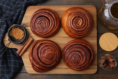 Photo of Delicious cinnamon rolls, sticks and powder on wooden table, flat lay