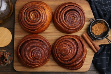 Photo of Delicious cinnamon rolls, sticks and powder on wooden table, flat lay