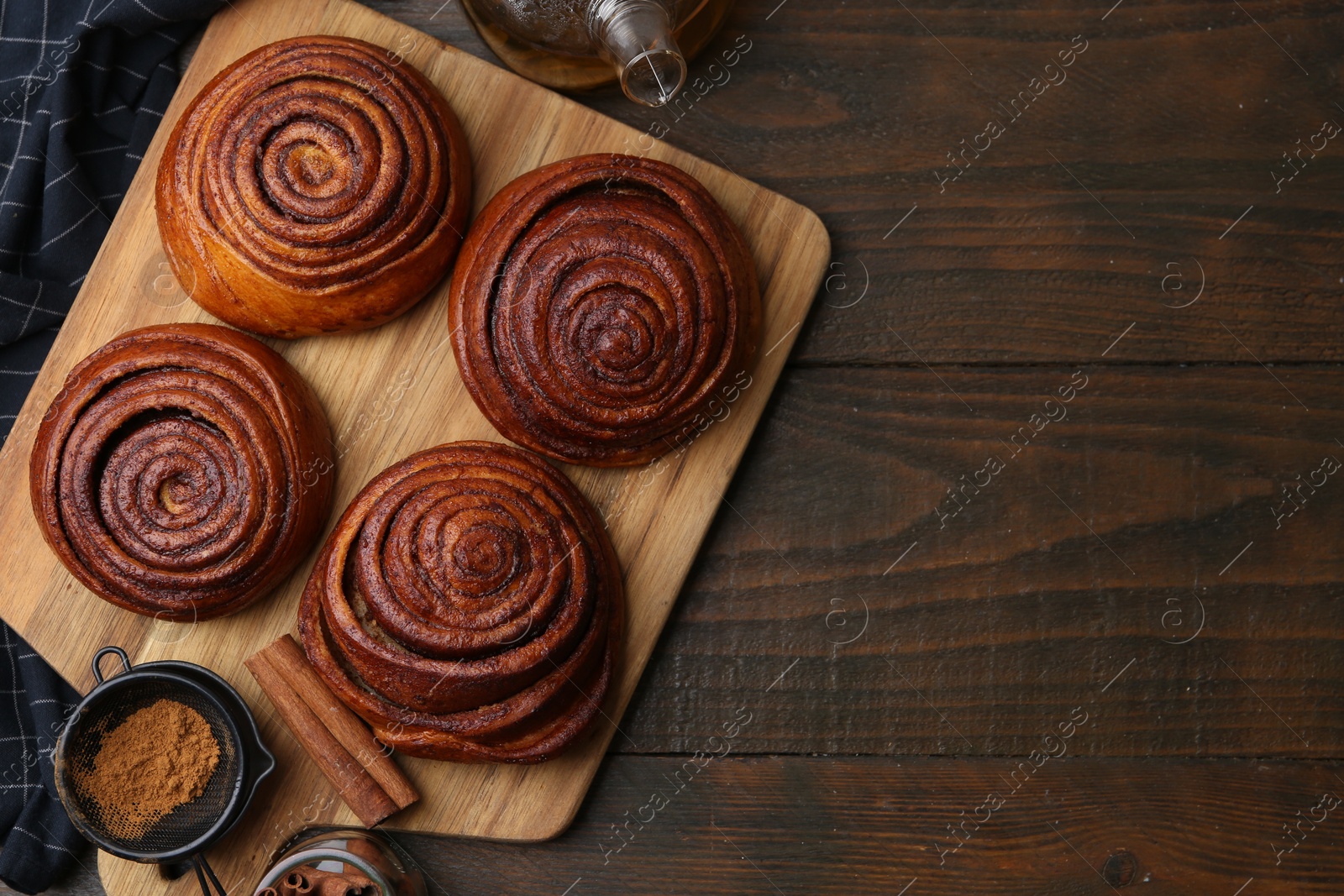 Photo of Delicious cinnamon rolls, sticks and powder on wooden table, flat lay. Space for text