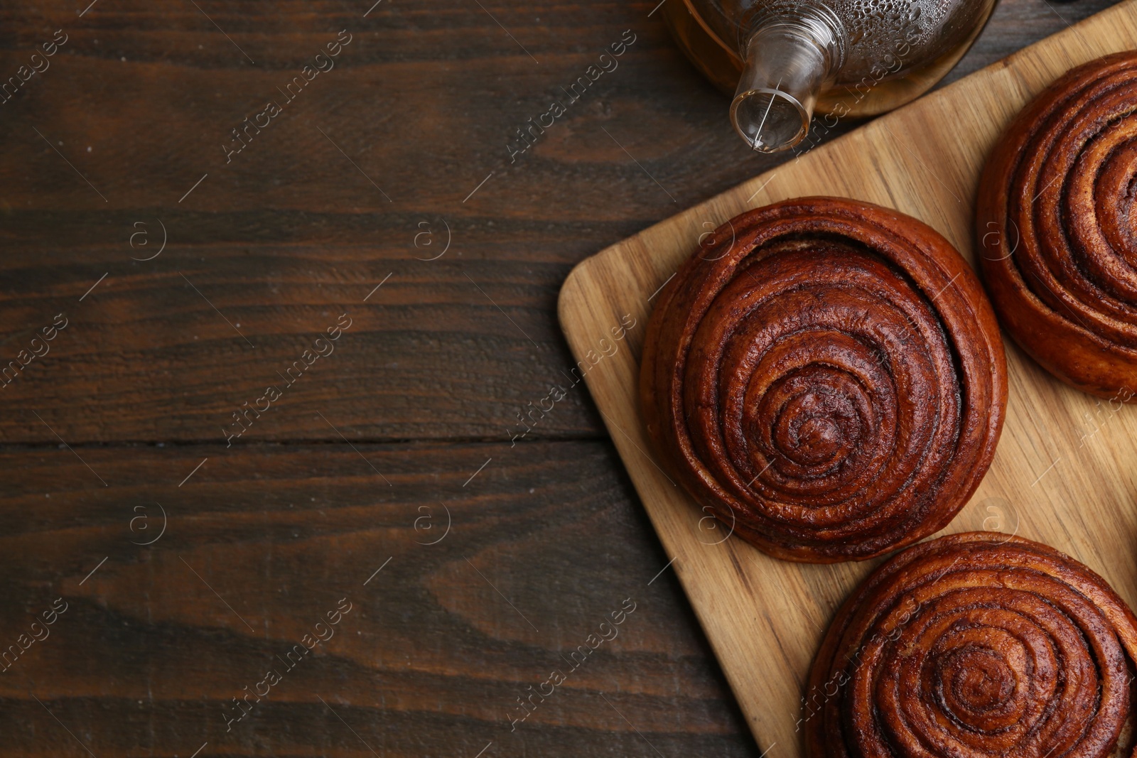 Photo of Delicious cinnamon rolls on wooden table, flat lay. Space for text