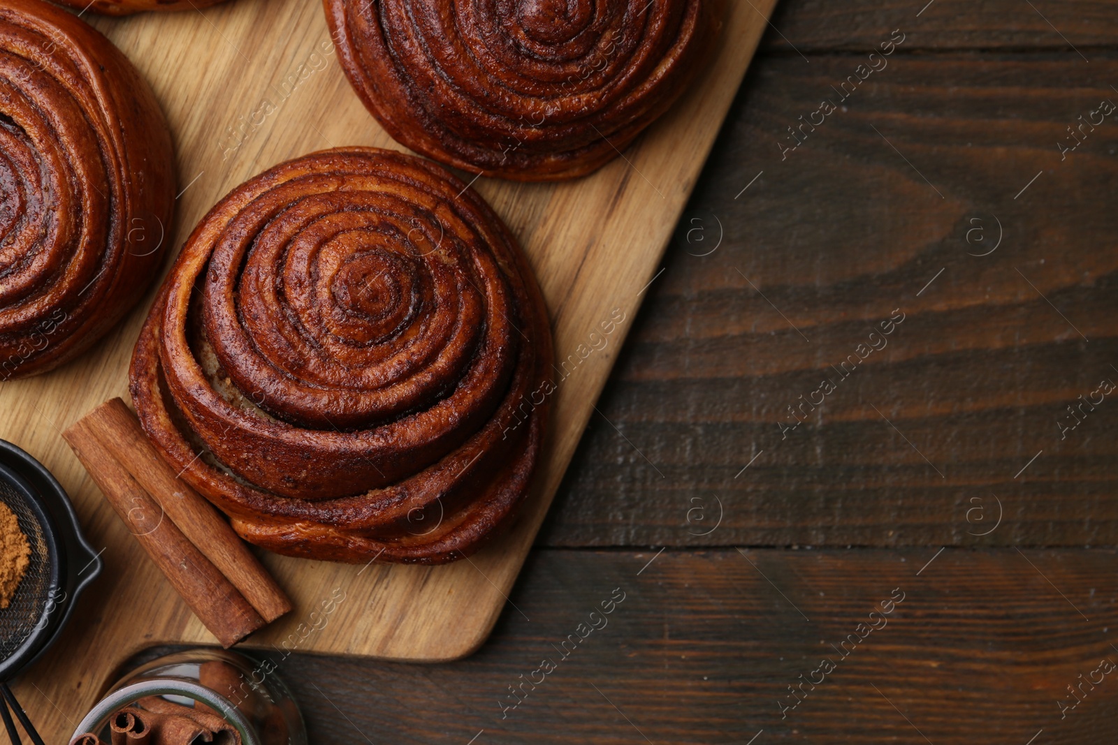 Photo of Delicious cinnamon rolls on wooden table, flat lay. Space for text