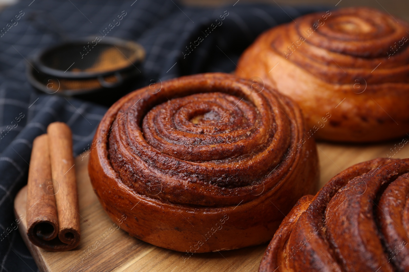 Photo of Delicious cinnamon rolls on wooden board, closeup