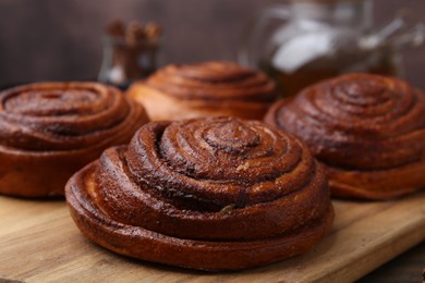 Photo of Delicious cinnamon rolls on wooden board, closeup