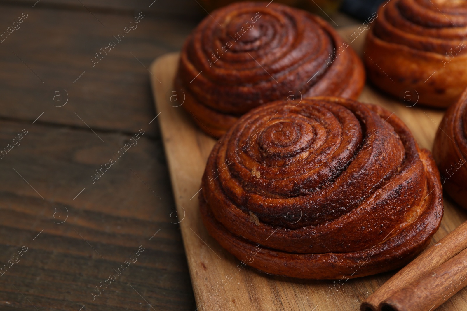 Photo of Delicious cinnamon rolls on wooden table, closeup. Space for text