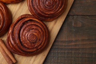 Photo of Delicious cinnamon rolls on wooden table, top view. Space for text