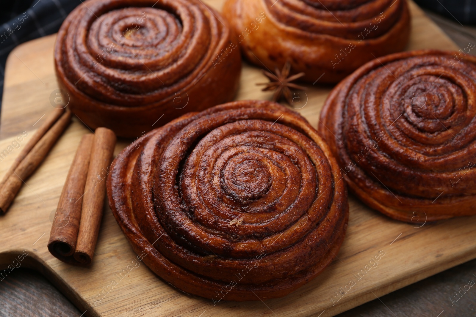 Photo of Delicious cinnamon rolls and spices on wooden table, closeup