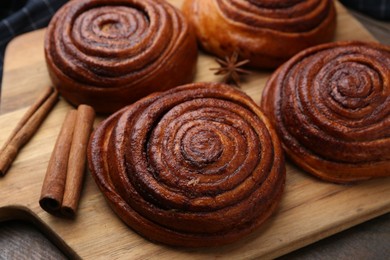 Photo of Delicious cinnamon rolls and spices on wooden table, closeup