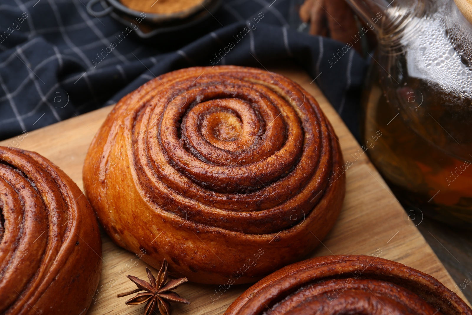 Photo of Delicious cinnamon rolls and anise star on table, closeup