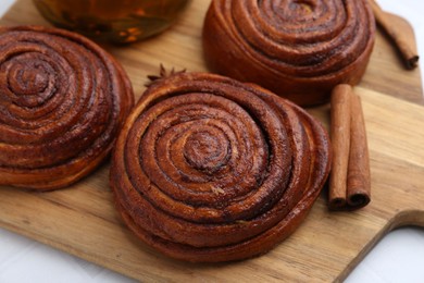 Photo of Delicious cinnamon rolls and spices on white table, closeup